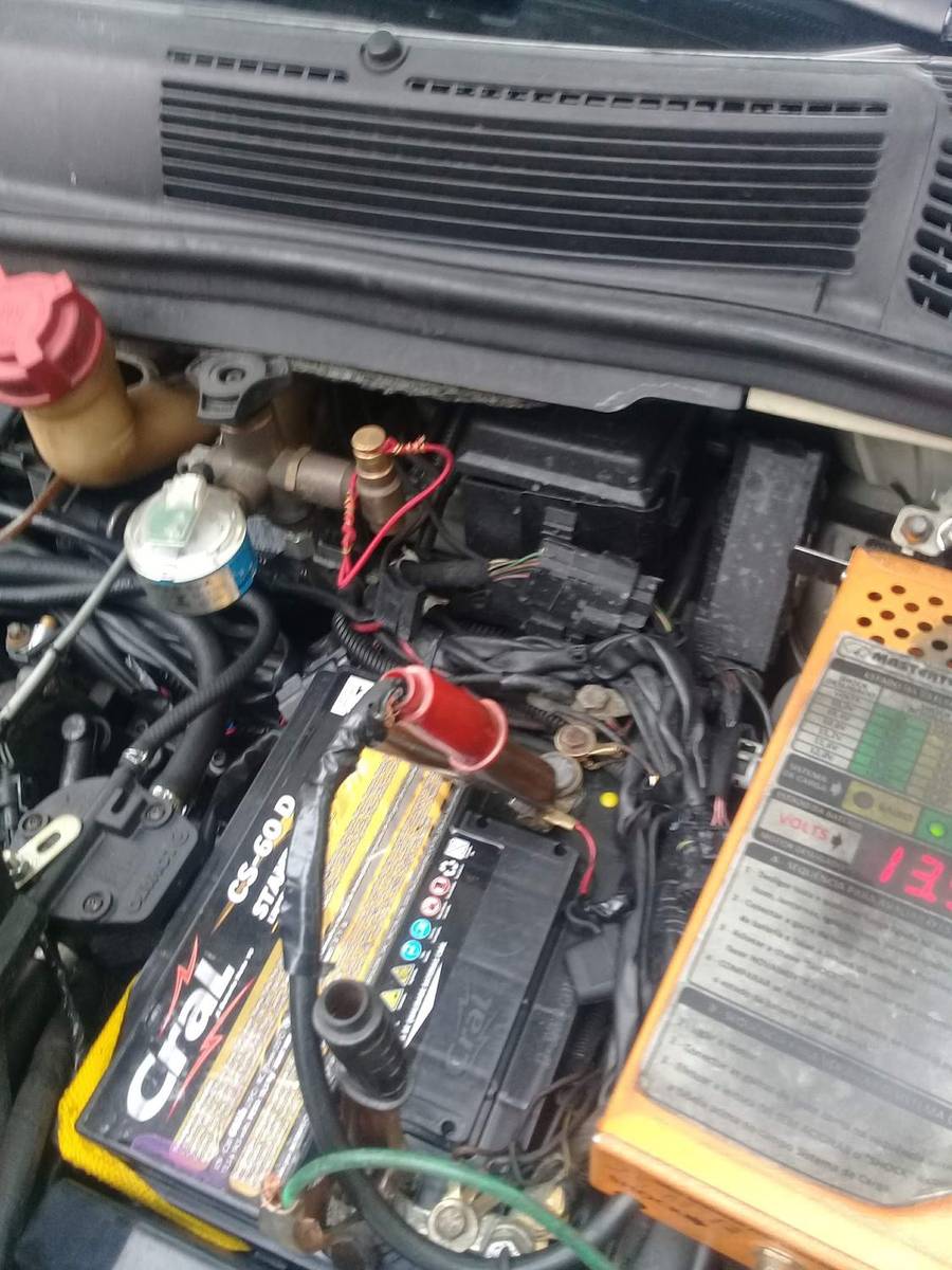 Vão de motor aberto com a bateria e cabos de teste ligados nos terminais